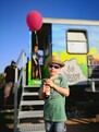 Kind mit Ballon und Getränk vor dem Waggon