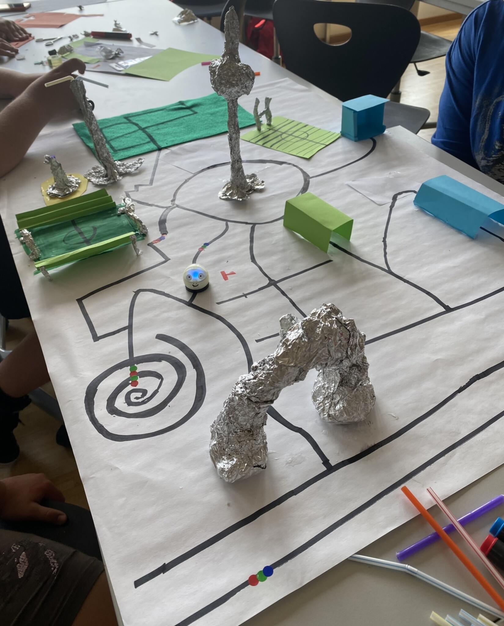 Kinder haben einen Stadplan und Gebäude gebastelt und programmieren Wege für die Ozobots