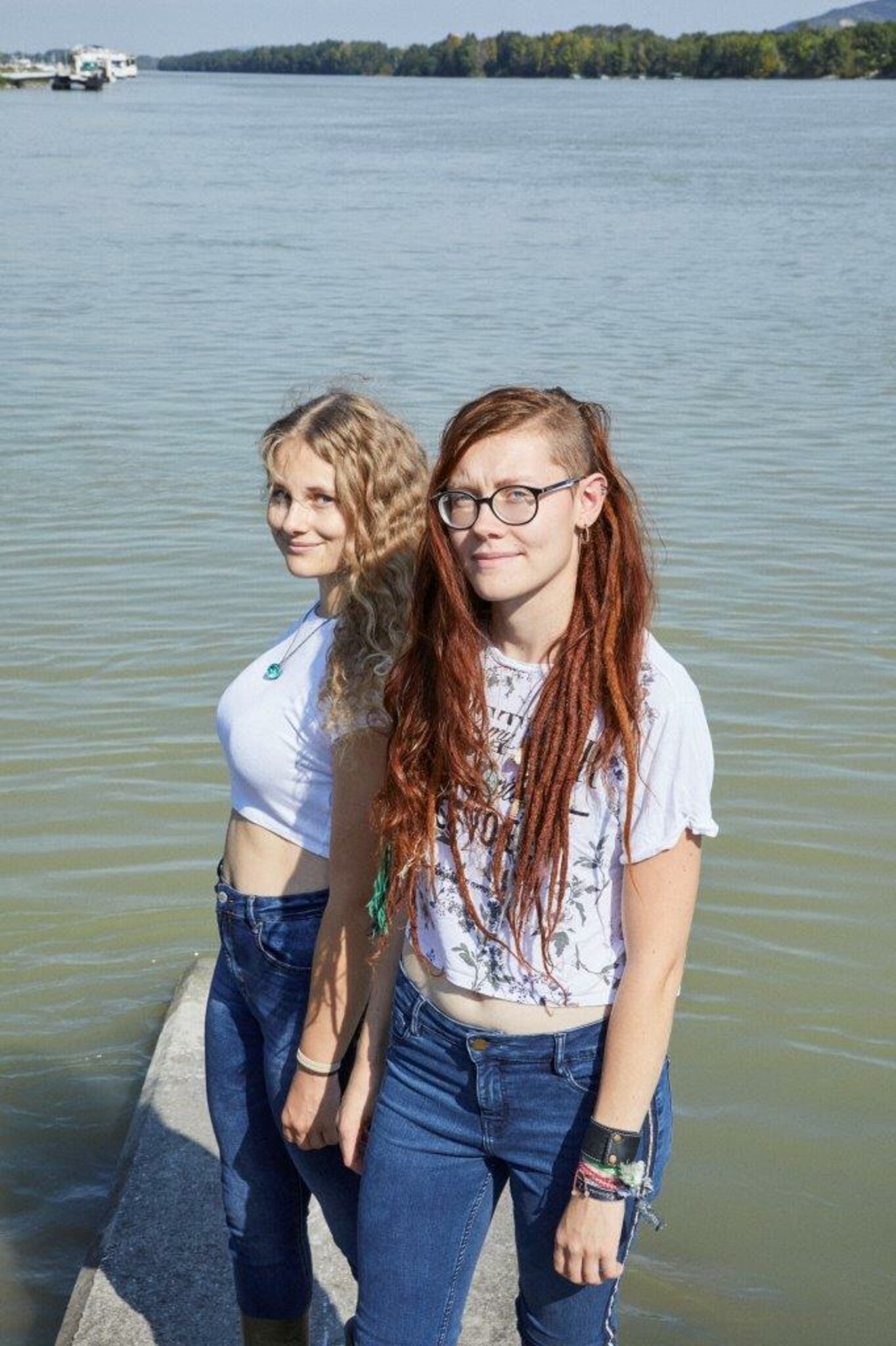 junge Frauen stehen auf einem Steg an einem See