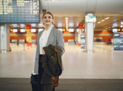 Junge Frau am Flughafen mit Mantel in der Hand